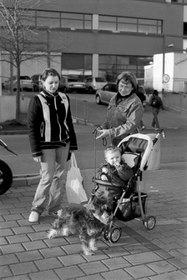 Drei Generationen mit Hund auf einem Parkplatz