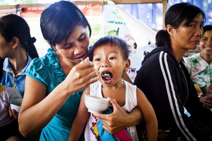 A child being fed at a nutrition support group meeting sponsored by UNICEF