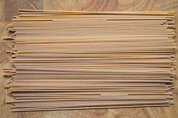 Organic whole grain spaghetti on wooden kitchen worktop.