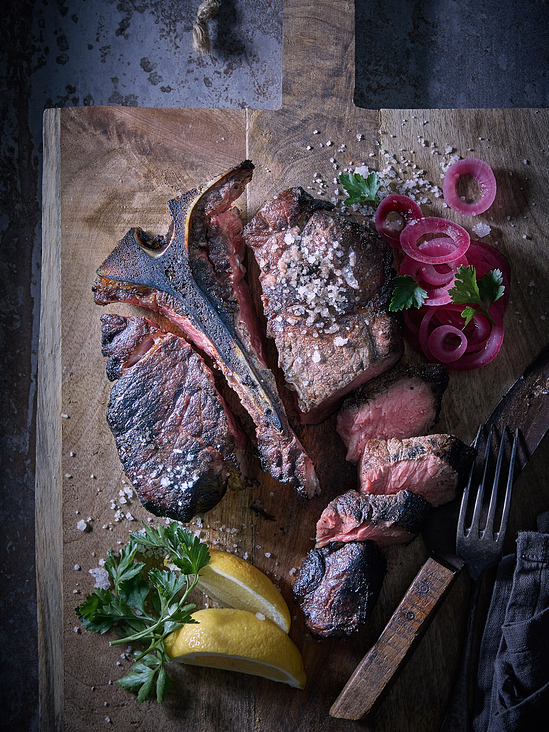 Marius Prions Photo FOOD / T-Bone Steak, auf Holzbrett, geschnitten