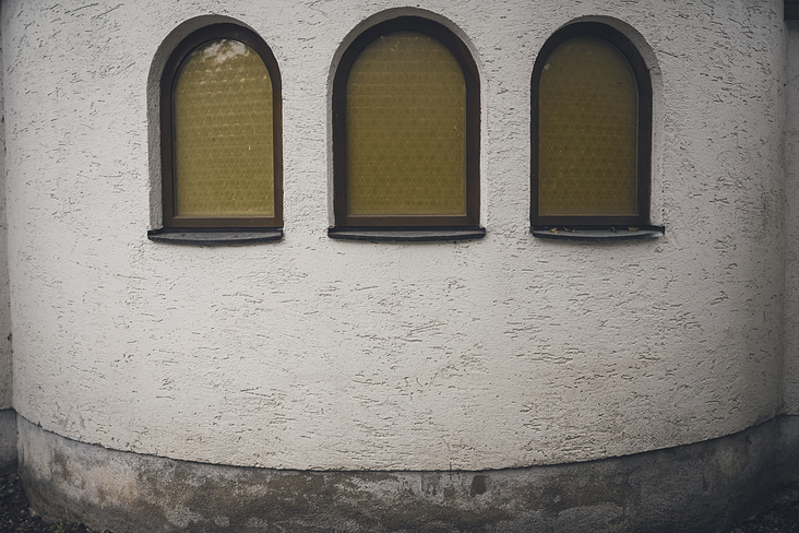 Drei gelbe Fenster und eine runde Wand