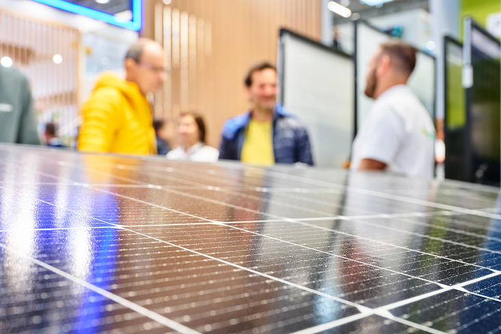 Solarpanel mit Standbesuchern im Hintergrund