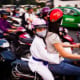 A young girl wearing a helmet in rush hour traffic in Saigon, Vietnam.